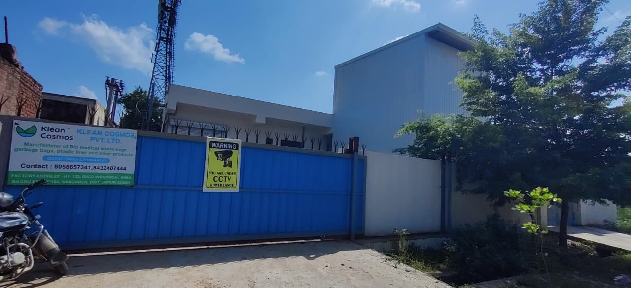 Entrance to the Klean Cosmos factory in Bagru, Jaipur — blue boundary wall with company signage and CCTV surveillance