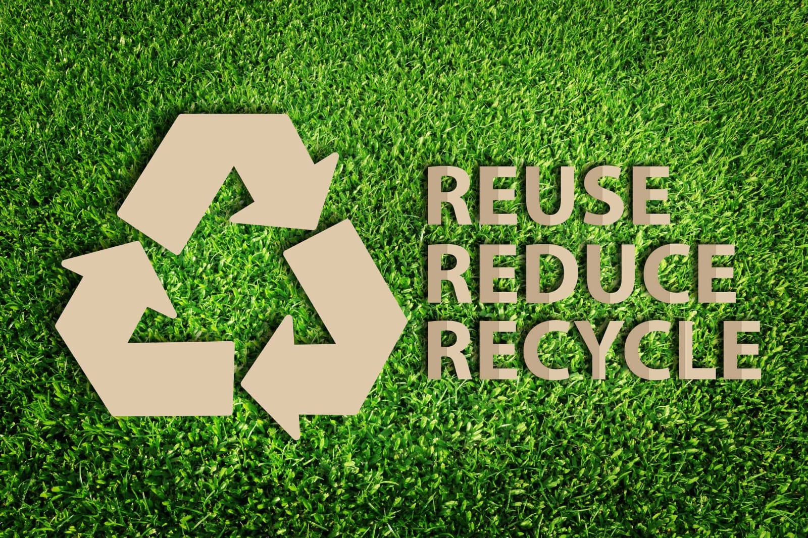 Reuse, Reduce, Recycle symbol on a grass background — representing IS/ISO 17088 compostable and biodegradable bags